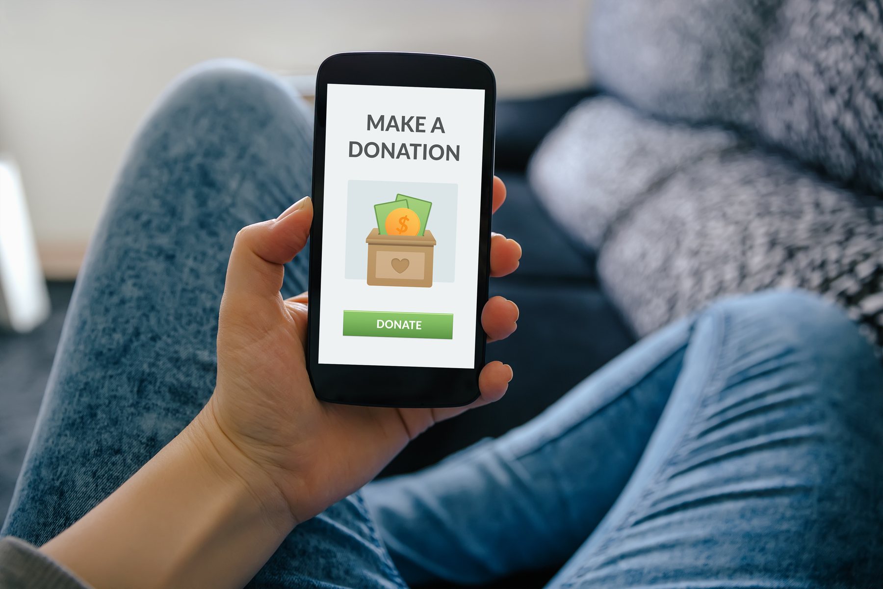 Closeup of a person’s hand holding a phone, promoting charitable donations for tax deductions.